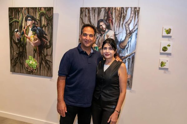a man and woman standing in front of paintings