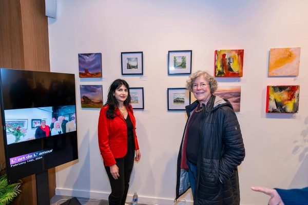 a couple of women standing in front of a wall with pictures