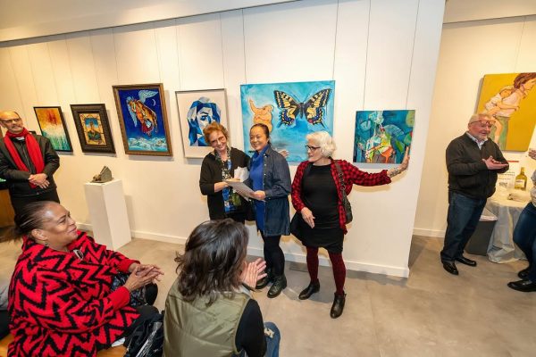 a group of people standing around a wall with paintings on it